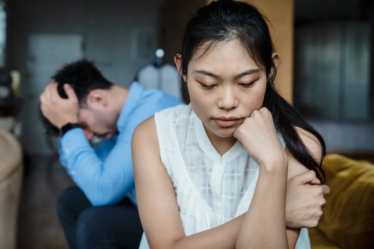 Couple on sofa showing signs he is emotionally unavailable in their relationship.